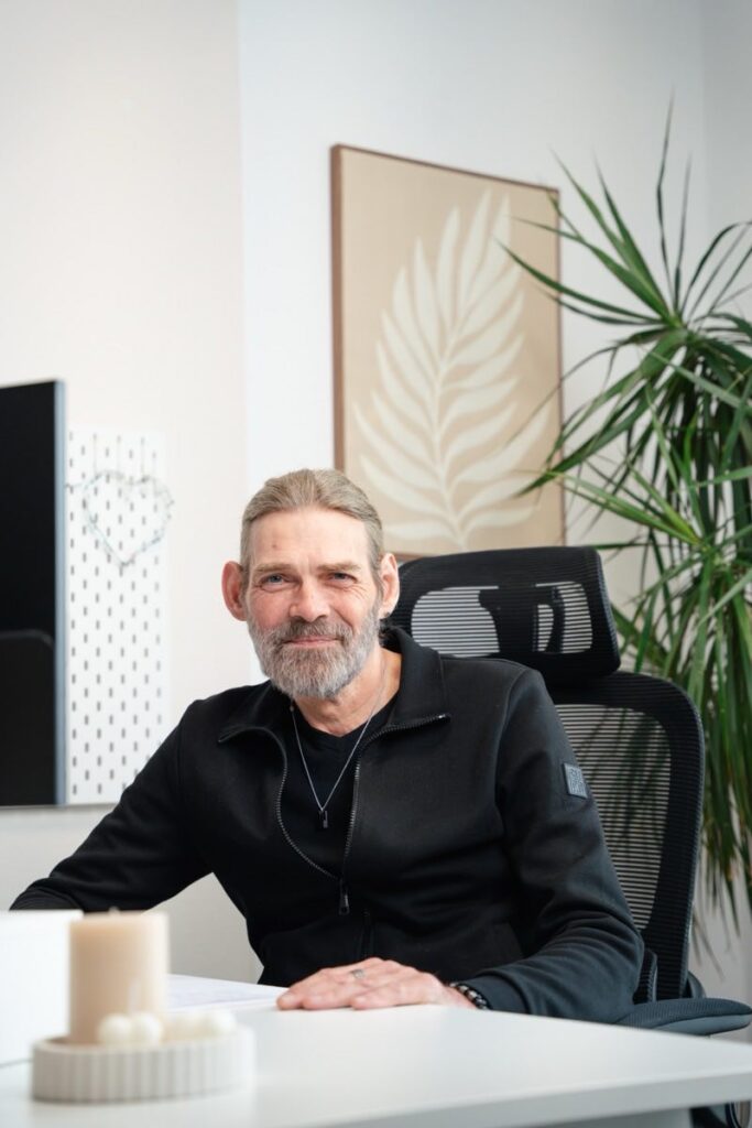 Mitarbeiter Georg Reichow sitzt am Schreibtisch im hellen Büro des Seniorenzentrums Lichtenberg